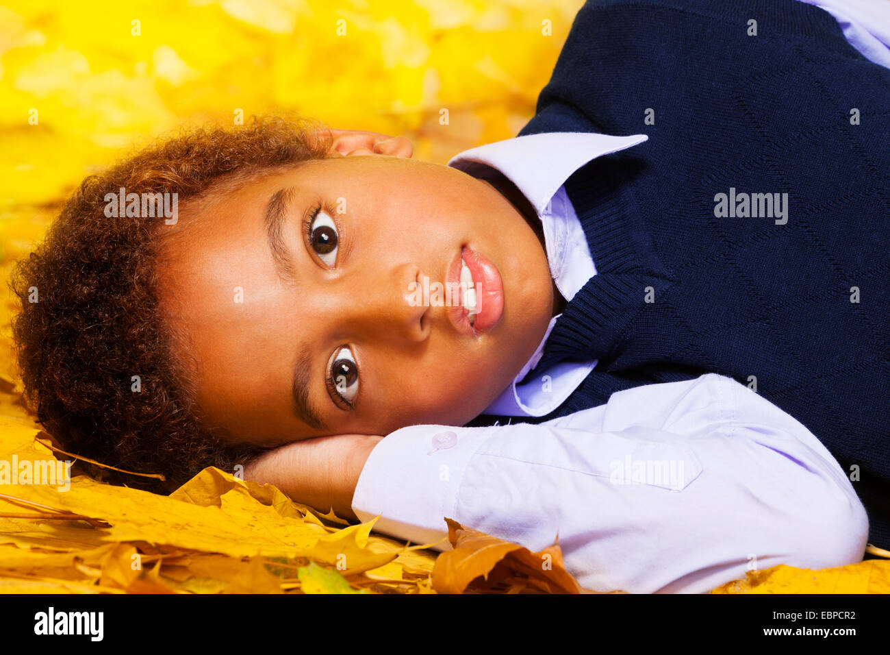 Petit garçon noir jette sur l'automne feuilles d'érable Banque D'Images