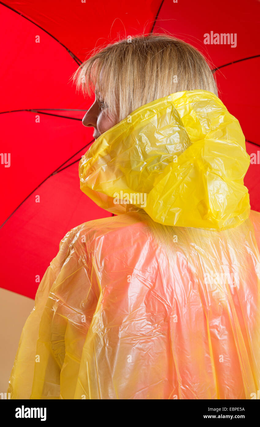 Woman holding poncho jaune parapluie rouge Banque D'Images