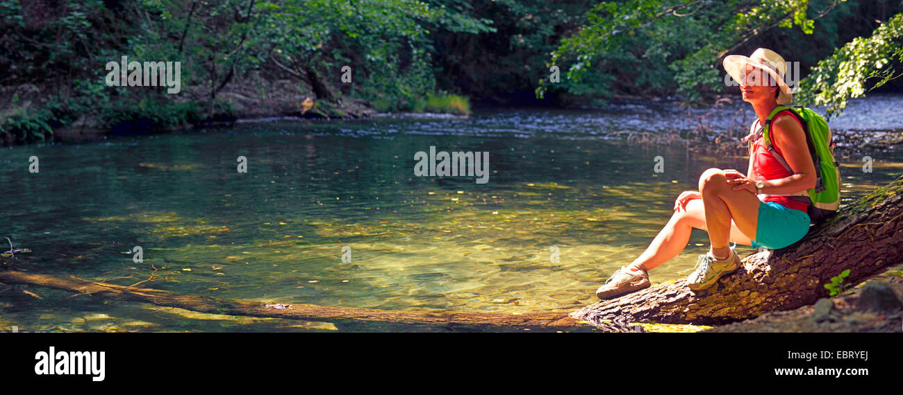Female hiker assis sur un tronc d'arbre et de faire une pause, France, Alpes Maritimes, Gorges de la Siagne, Monsanto Banque D'Images