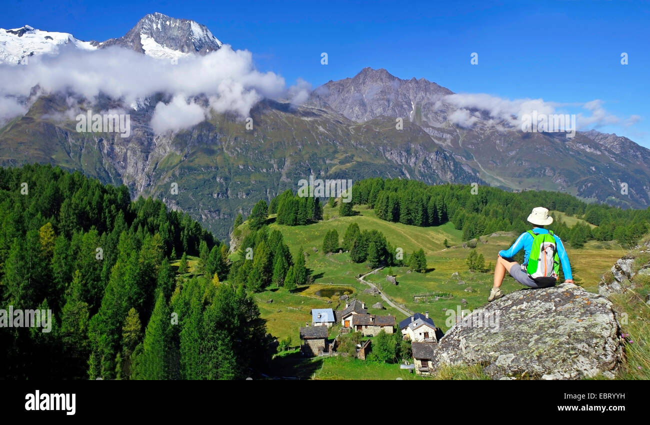 Wanderer femme assise sur un rocher et à la recherche à Little village de Le Monal et le Mont Pourri, France, Savoie, Parc National de la Vanoise, Sainte-Foy-Tarentaise Banque D'Images