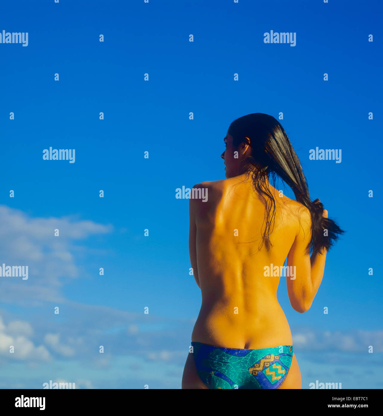 Vue arrière du topless young woman holding her hair against blue sky Guadeloupe Banque D'Images