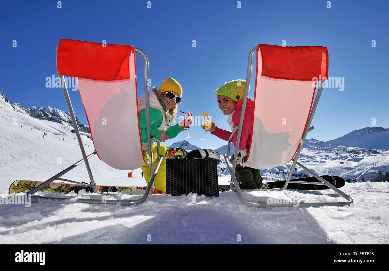 Deux adolescents assis sur chaises en toile dans la neige et de boire des cocktails, France Banque D'Images