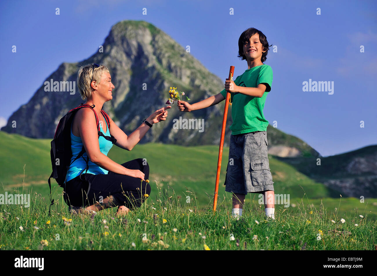 Garçon remise d'un bouquet de fleurs cueillies à sa mère durant la marche-tour dans les Alpes, France Banque D'Images