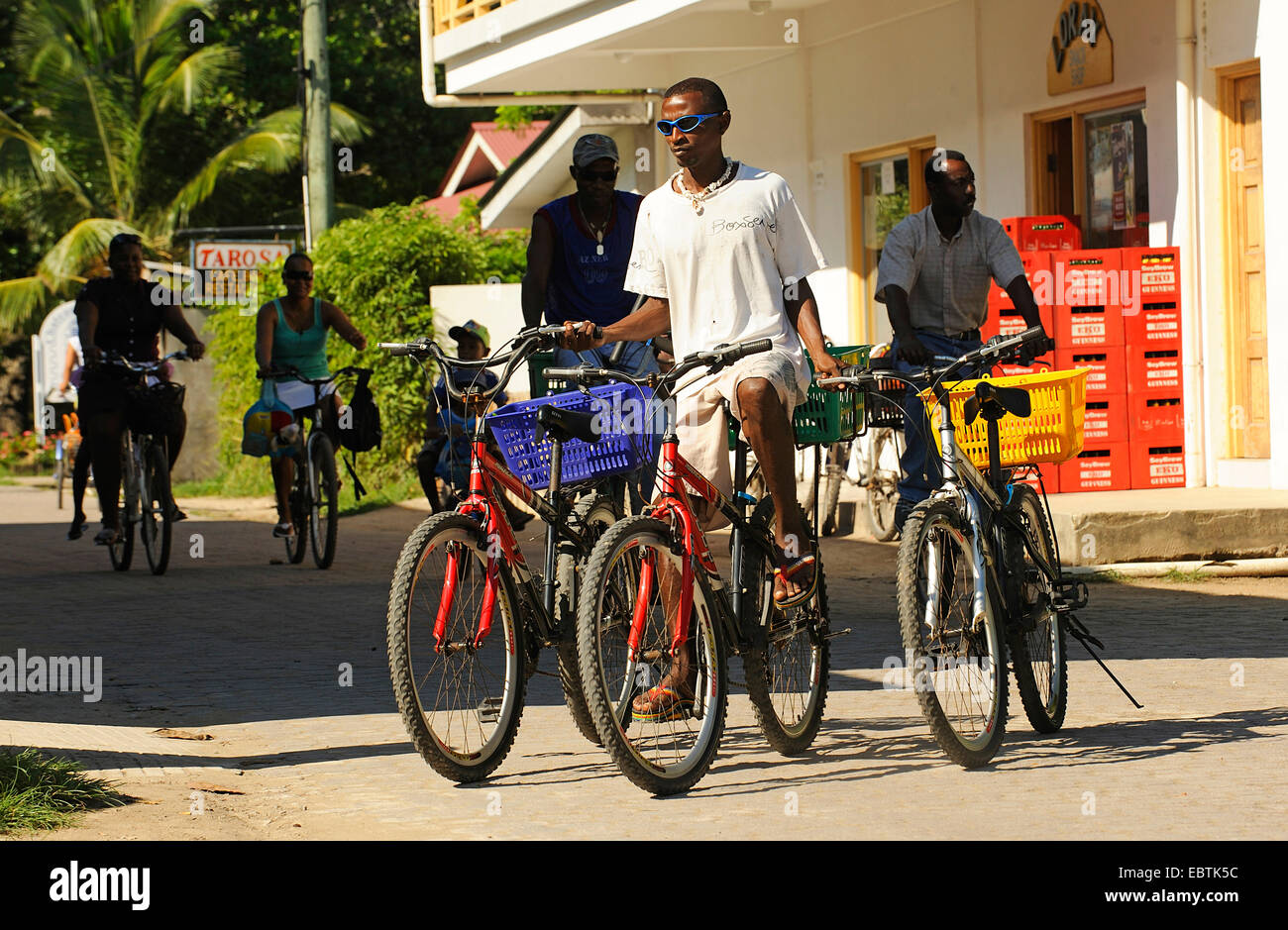 Jeune homme à vélo et transport dans chaque main un autre vélo, Seychelles Banque D'Images