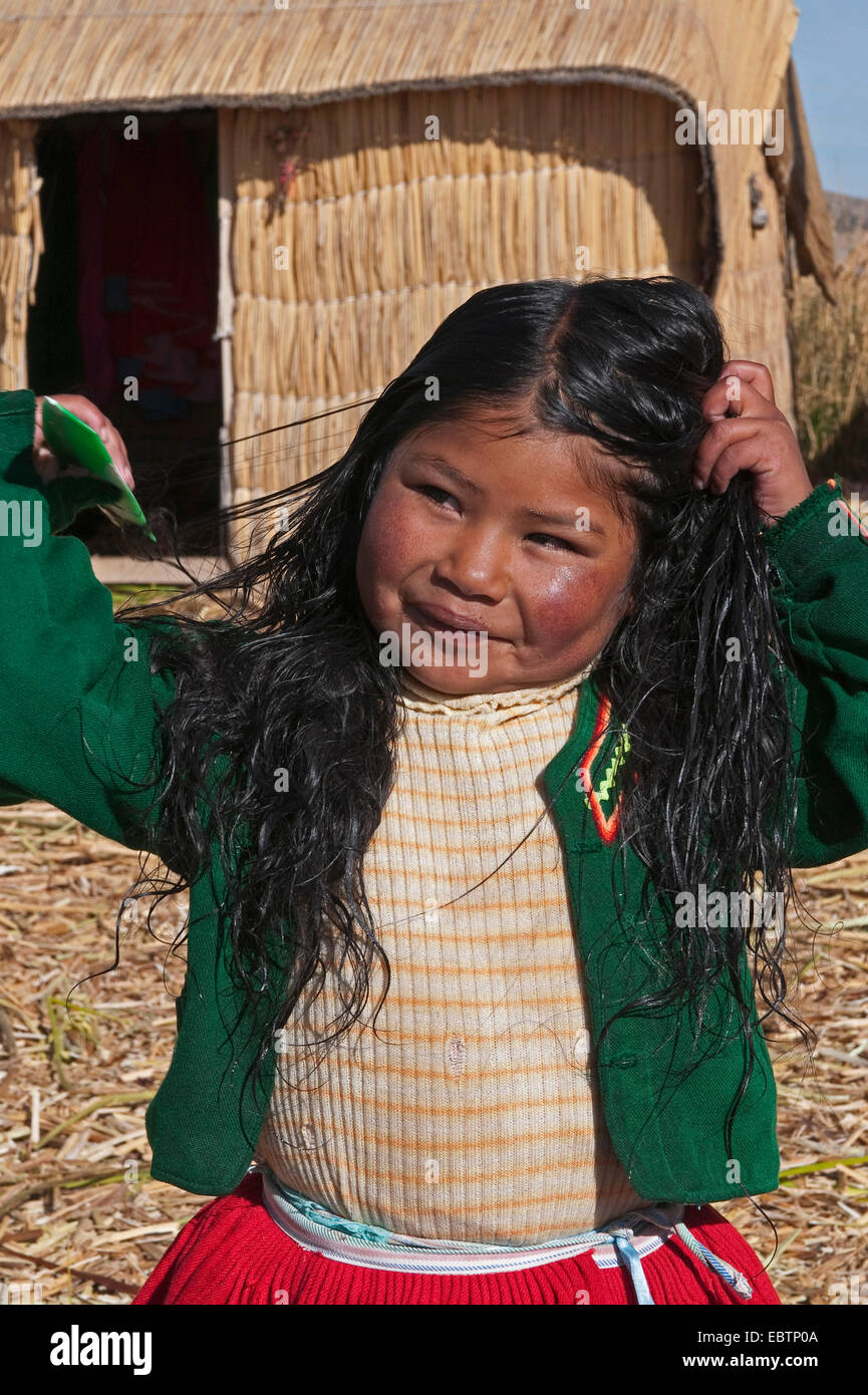 Le quechua ou l'Uros Indian girl sur l'une des 42 îles flottantes sur le lac Titicaca appelé "des îles Uros, l'auto-construction de Totora roseaux, le Pérou, le Lac Titicaca, l'Île Uros Banque D'Images