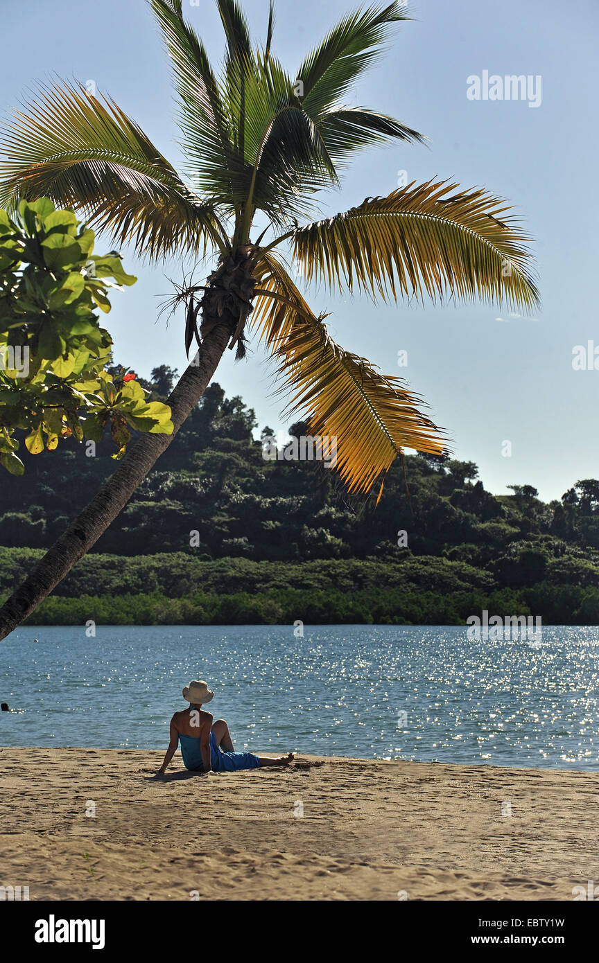 Femme assise sous palmier au sable, Madagascar, Nosy Be Banque D'Images