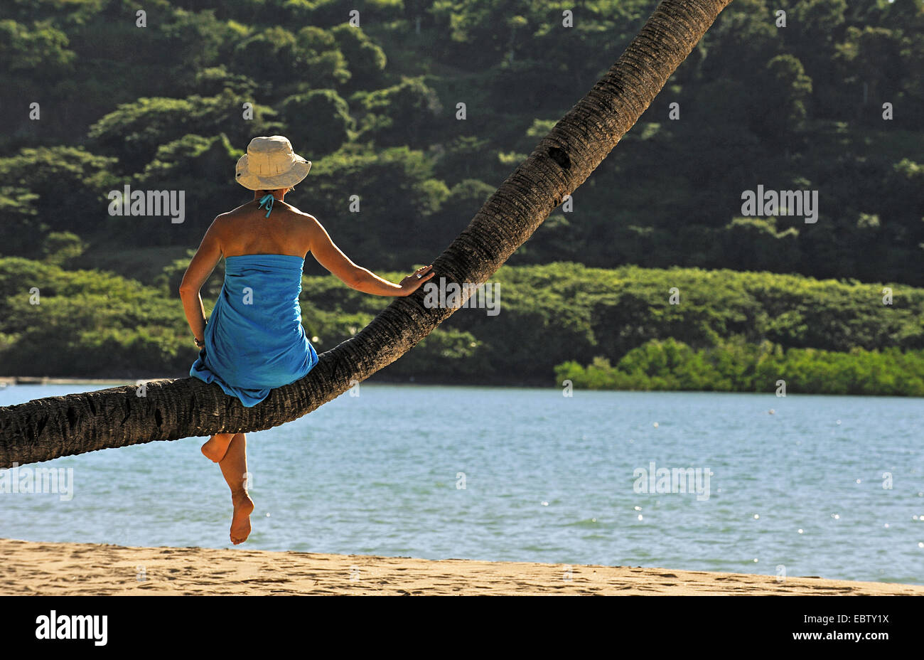 Woman sitting on palm tree à sandy beach, Madagascar, Nosy Be Banque D'Images