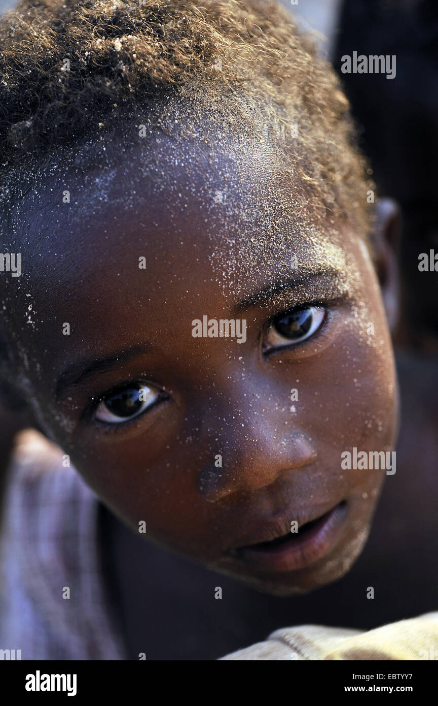 Petit garçon à la peau sombre avec du sable sur le visage, Madagascar, Nosy Be Banque D'Images