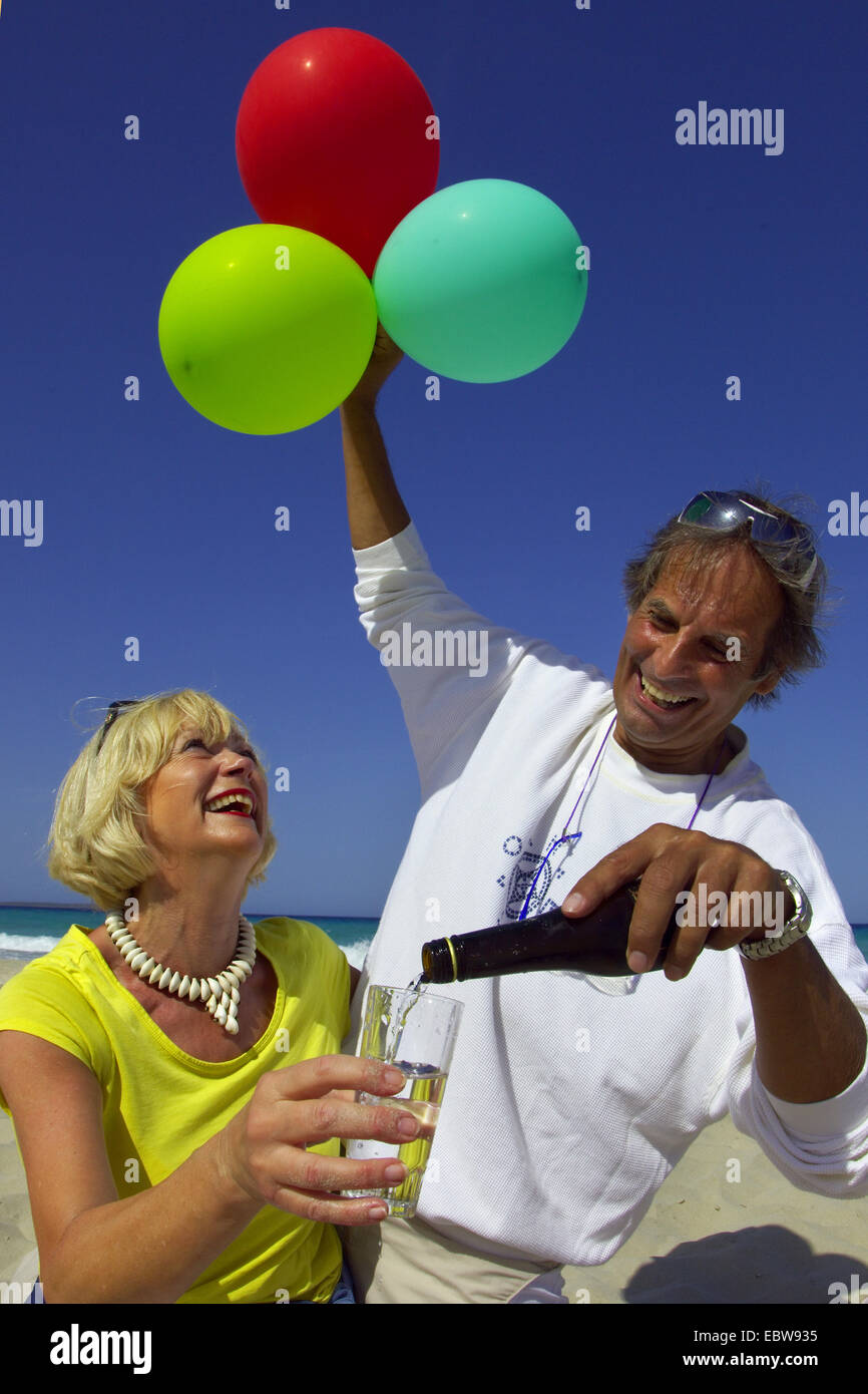 Personnes âgées couples célébrant avec ballons d'air sur la plage Banque D'Images