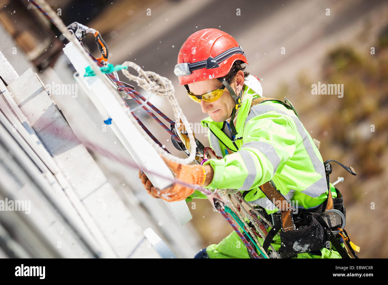 Grimpeur industrielle plaçant une feuille de polystyrène pour l'isolation d'un mur de l'édifice Banque D'Images