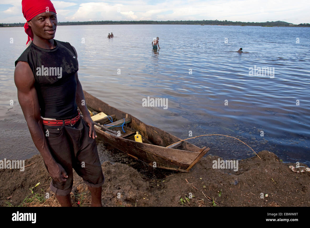 Jeune pêcheur debout devant son bateau au Lac Kivu dans lequel d'autres hommes sont de se laver, de l'Ouganda, Kivusee, Entebbe Banque D'Images