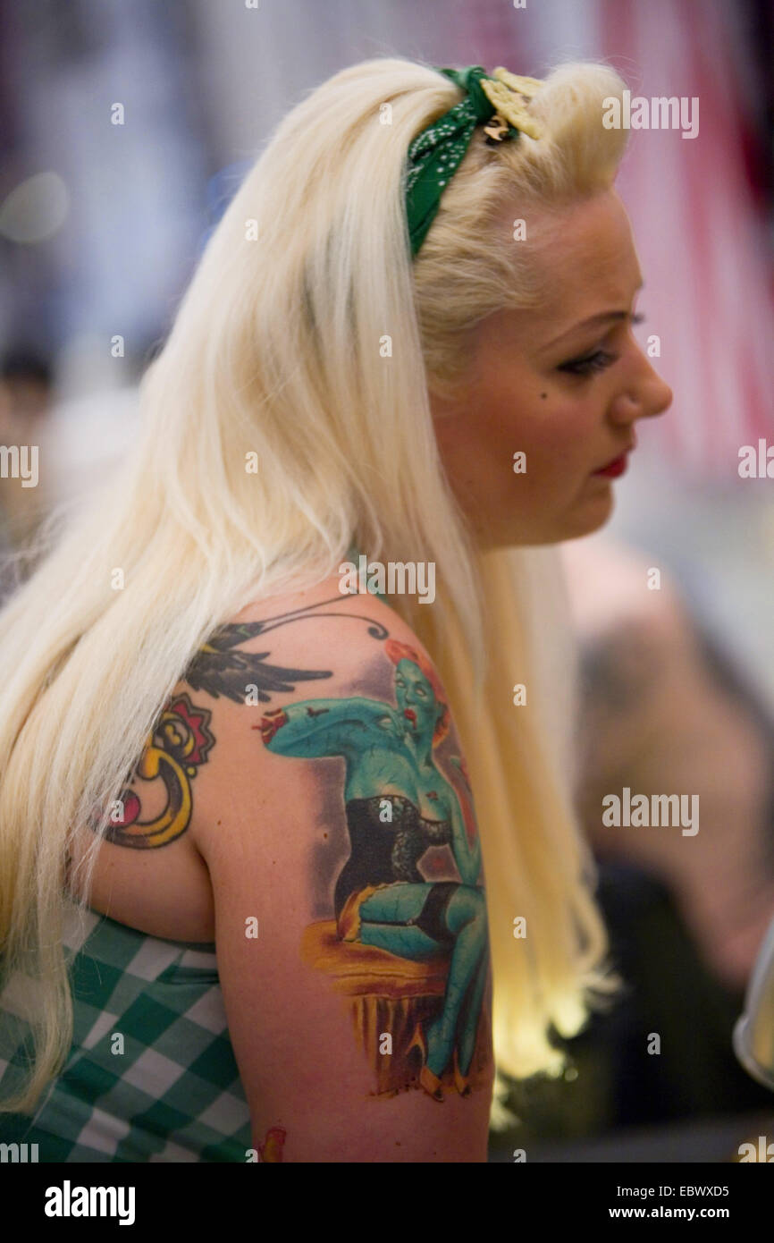 Jeune femme blonde avec un tatouage sur le bras supérieur en attente dans une boutique de tatouage, Allemagne Banque D'Images