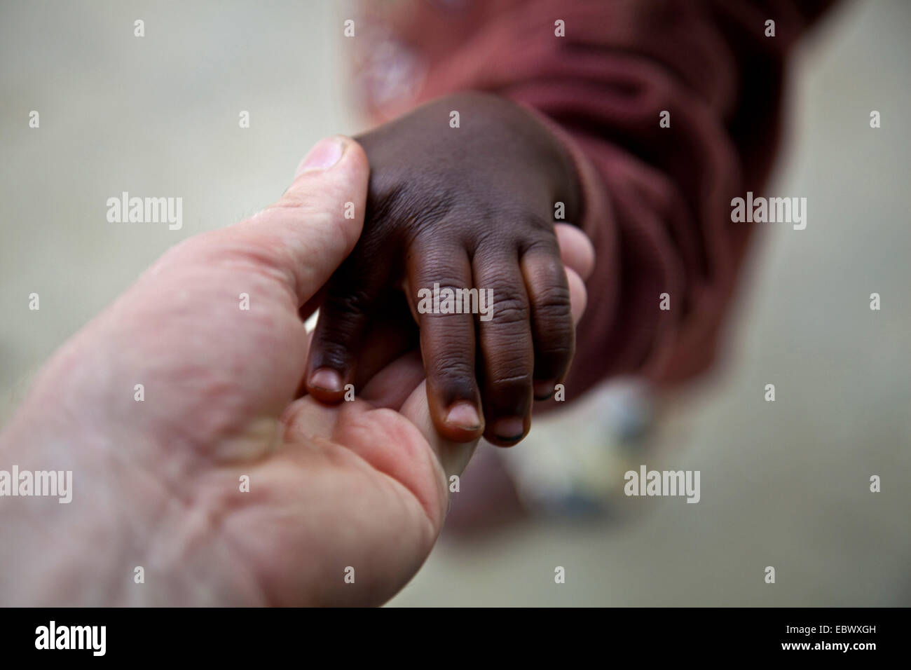 Adultes blanc tendre la main à l'enfant africain, le Burundi, Karuzi, Buhiga Banque D'Images