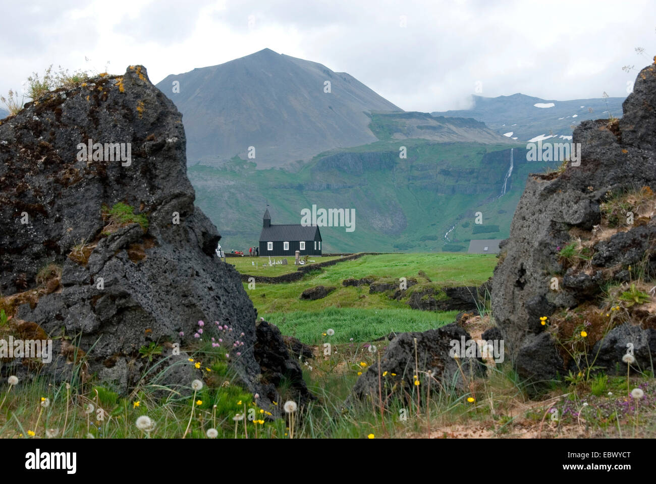 Vue à travers deux rochers de lave de la 'Budahraun' à la petite église en bois 'Budirkirkja' en face des montagnes, l'Islande, Snaefellsness, Bir Banque D'Images