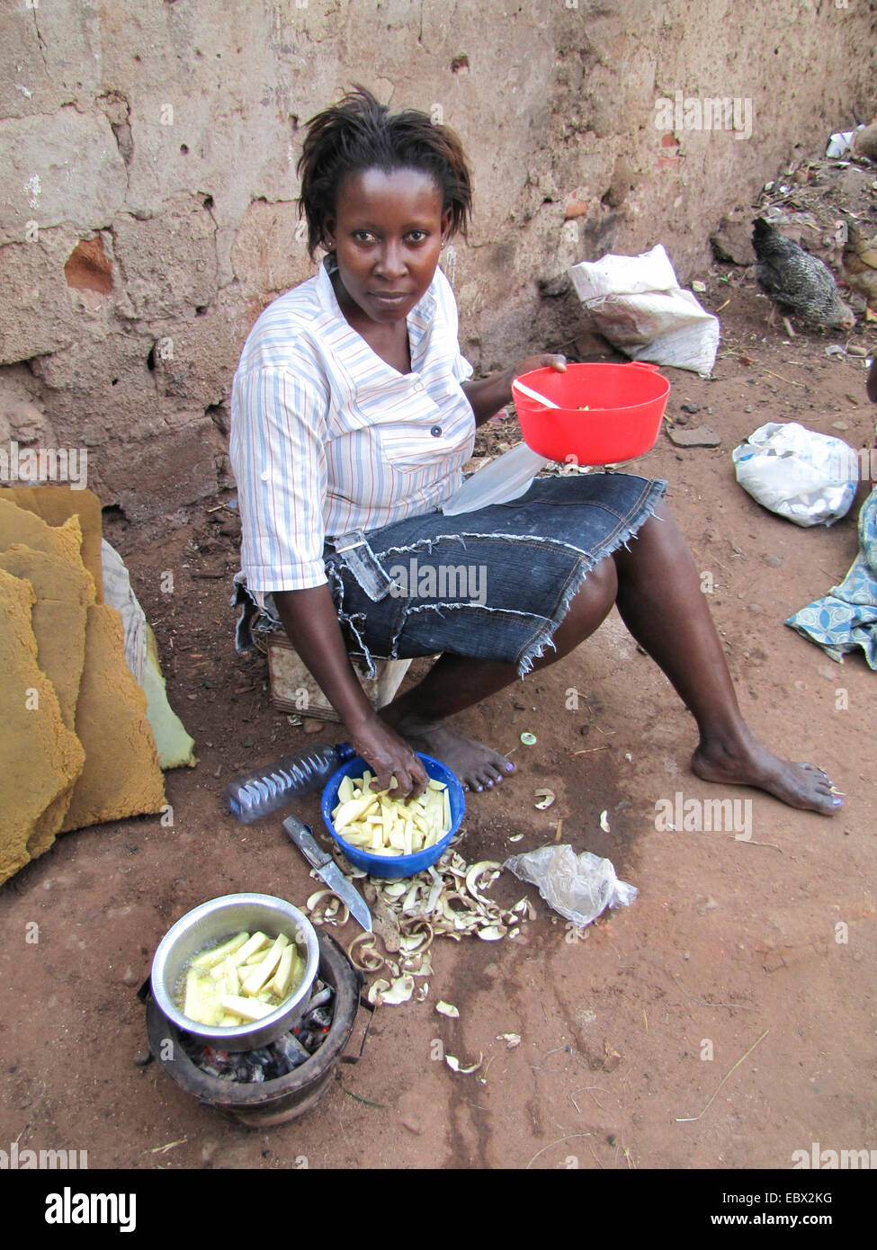 Femme est la friture croustilles de pommes de terre sur le sol de terre d'une cour, au Burundi, Bujumbura mairie, Bujumbura, Bwiza Banque D'Images