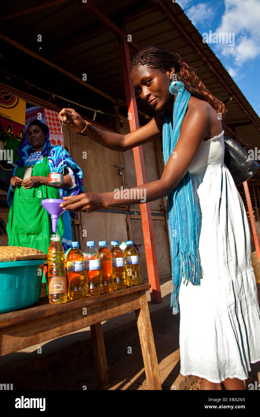 Jeune femme la mise en bouteille de l'huile de cuisson sur le marché, au Rwanda, Kigali, Nyamirambo Banque D'Images