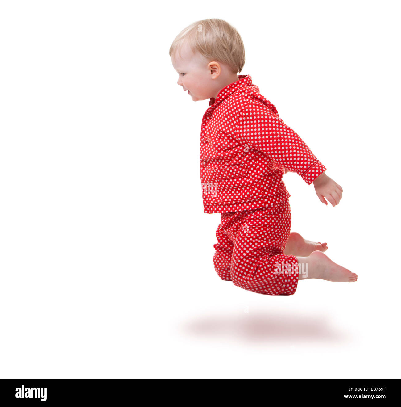 2 ans bébé fille en pyjama rouge jumping Banque D'Images