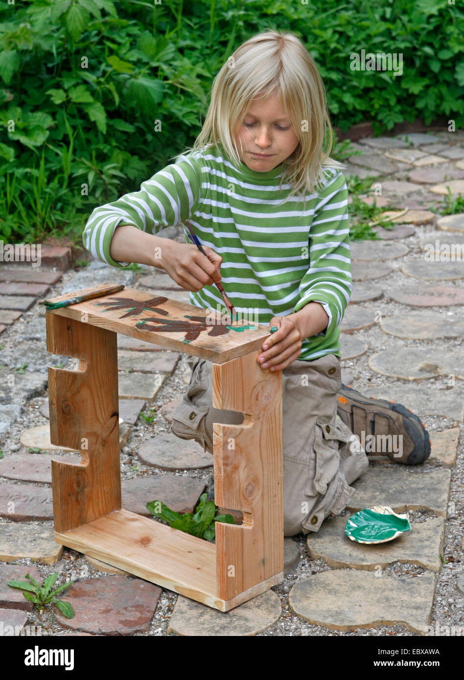 Les enfants font des un apple bouteille ; garçon est fini sa peinture bouteille apple dans des couleurs vives, Allemagne Banque D'Images