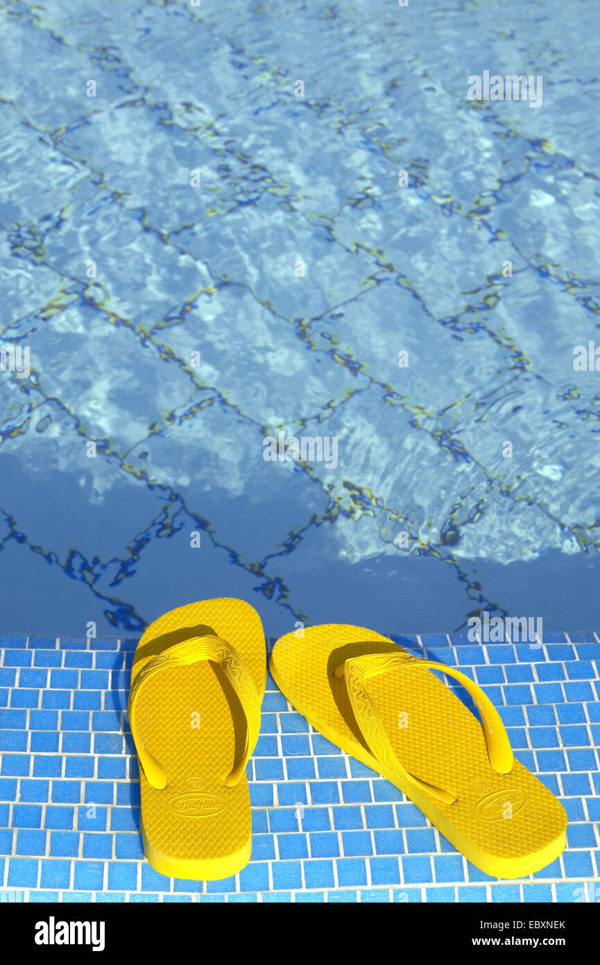 Thongs jaunes au bord de la piscine Banque D'Images