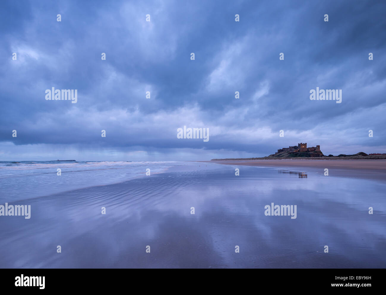 Stormclouds réfléchir sur la plage déserte à côté de Château de Bamburgh, Northumberland, Angleterre. L'hiver (mars) 2014. Banque D'Images