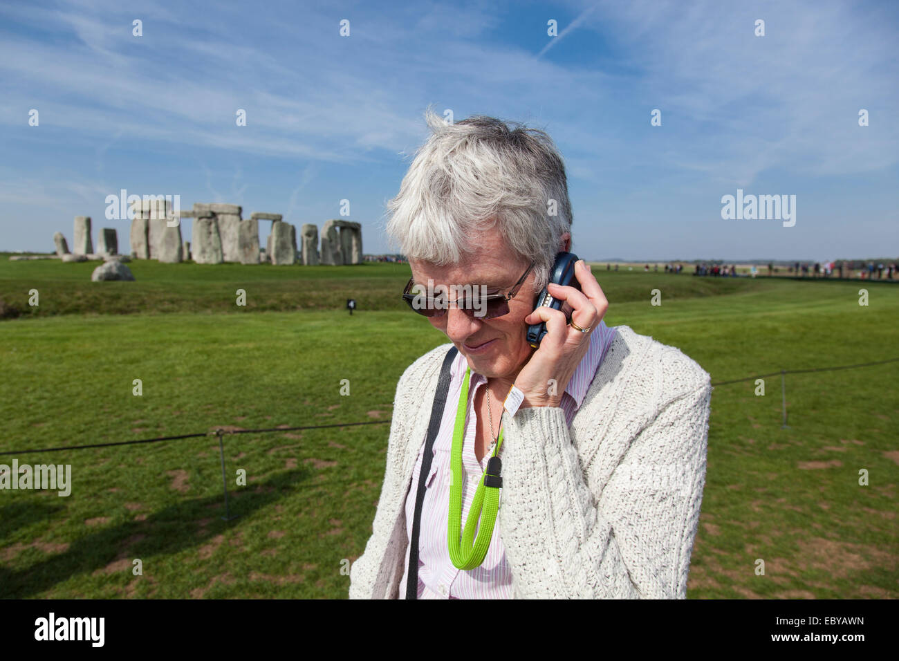 Femme visiteur de Stonehenge à l'écoute des informations sur les pierres à l'aide d'un récepteur sans fil. Banque D'Images
