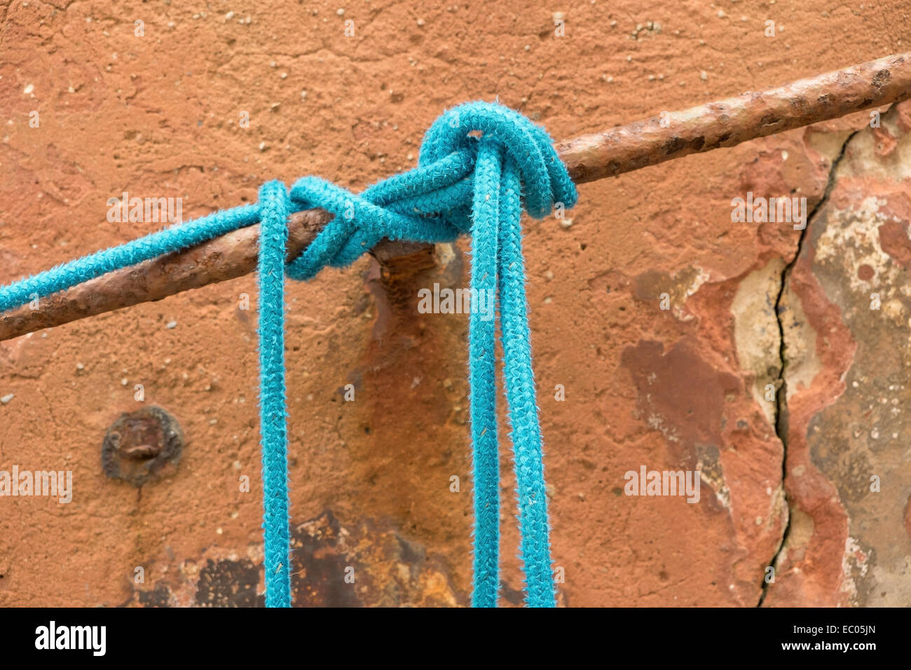 Un nylon bleu corde d'amarrage d'un bateau, attaché à une barre d'un port de pêche. Banque D'Images