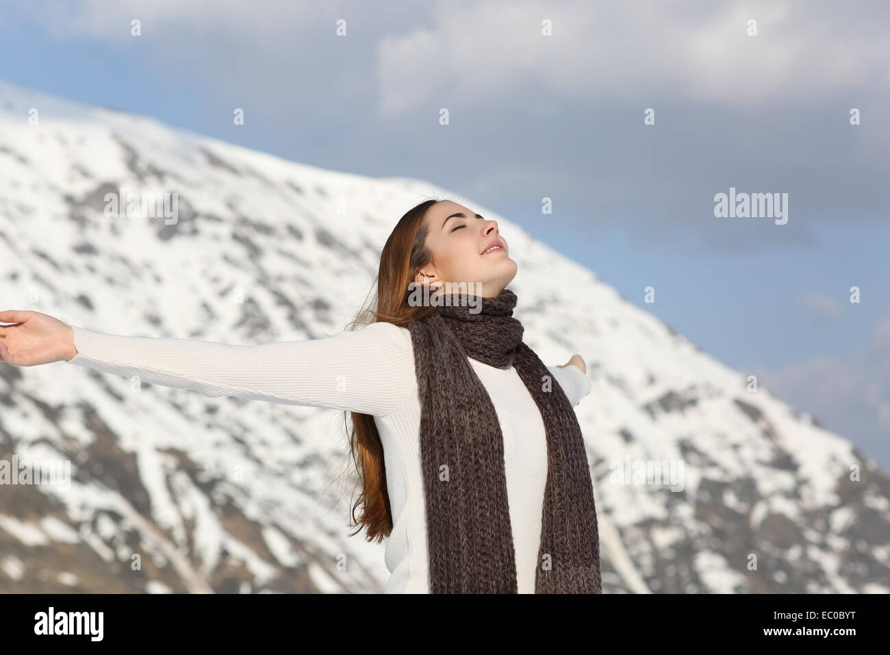 Femme de respirer l'air frais raising arms en hiver avec la montagne enneigée en arrière-plan Banque D'Images