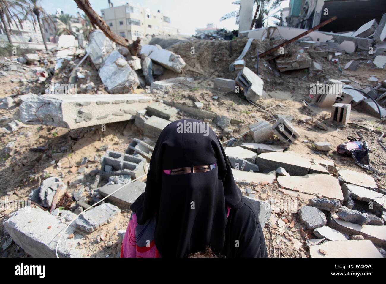 La ville de Gaza, bande de Gaza, territoire palestinien. 7 Décembre, 2014. Supportrice palestiniens du Front populaire de libération de la Palestine (FPLP) s'assoit à côté de l'immeuble endommagé lors d'une protestation contre le retard dans l'acquisition de matériel de construction en face de l'Office des Nations Unies à Gaza le 7 décembre 2014. Des responsables palestiniens ont déclaré le mois dernier, qu'au moins 100 camions de matériaux de construction par jour sont nécessaires pour achever la reconstruction de Gaza dans les trois années de crédit : Ashraf Amra/APA/Images/fil ZUMA Alamy Live News Banque D'Images