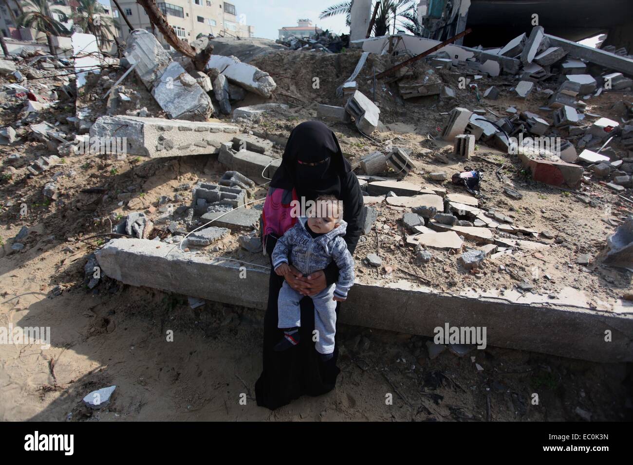 La ville de Gaza, bande de Gaza, territoire palestinien. 7 Décembre, 2014. Supportrice palestiniens du Front populaire de libération de la Palestine (FPLP) s'assoit à côté de l'immeuble endommagé lors d'une protestation contre le retard dans l'acquisition de matériel de construction en face de l'Office des Nations Unies à Gaza le 7 décembre 2014. Des responsables palestiniens ont déclaré le mois dernier, qu'au moins 100 camions de matériaux de construction par jour sont nécessaires pour achever la reconstruction de Gaza dans les trois années de crédit : Ashraf Amra/APA/Images/fil ZUMA Alamy Live News Banque D'Images