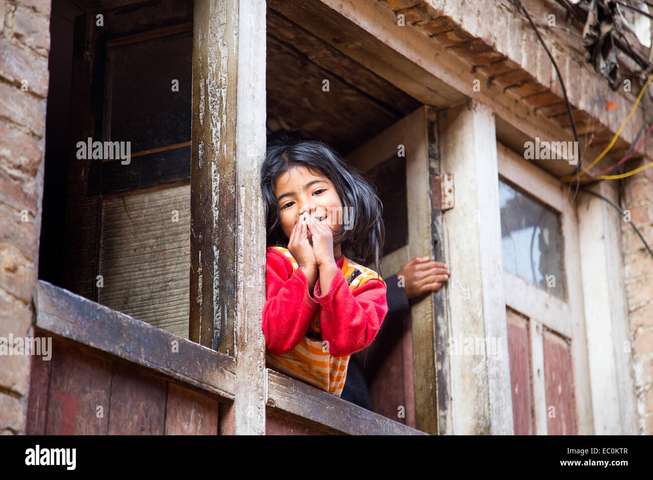 Namaste, jeune fille Napali dans une fenêtre à Bhaktapur, Népal Banque D'Images