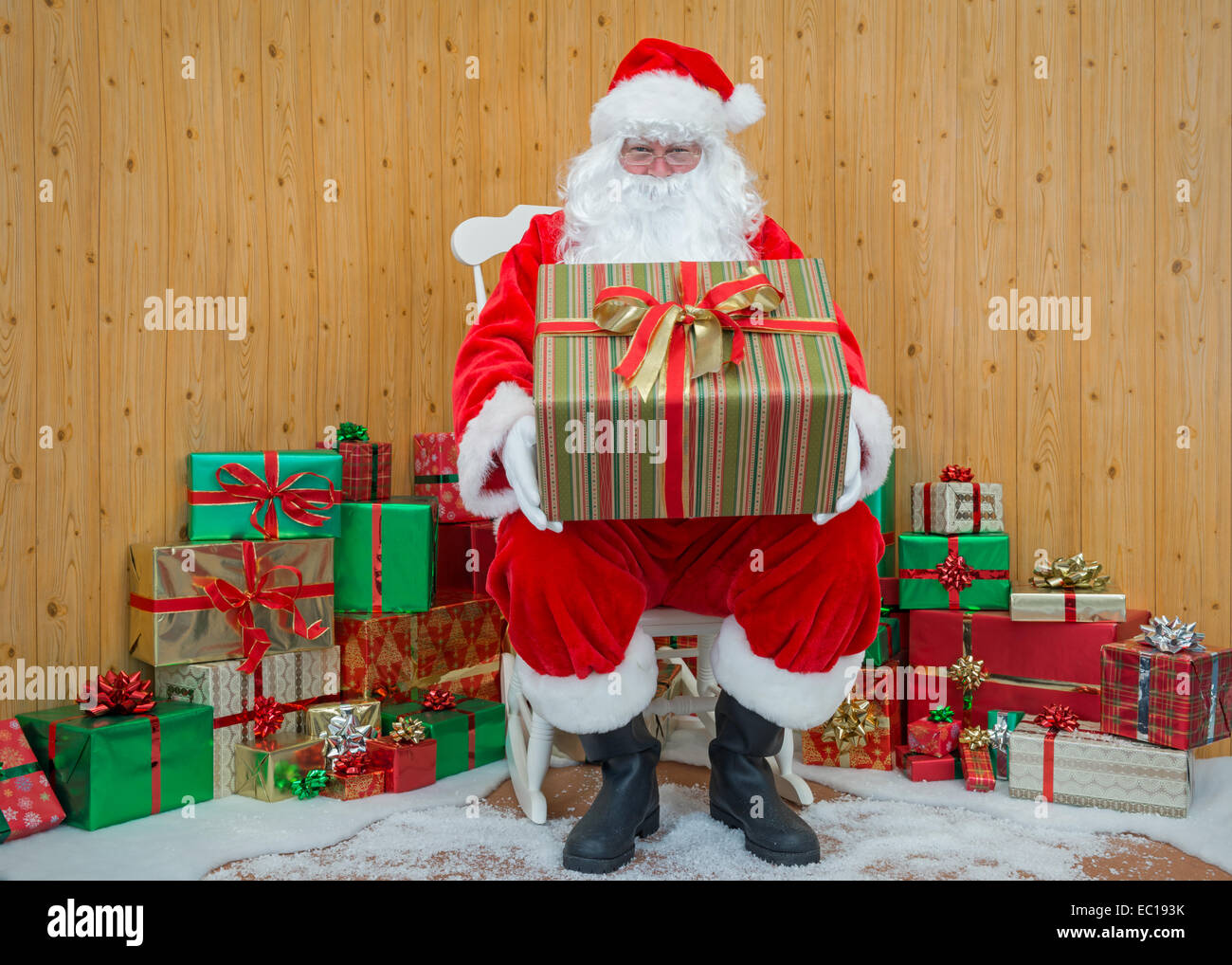 Le Père Noël / Père Noël assis dans sa grotte, tenant un gift wrapped present pour vous. Banque D'Images