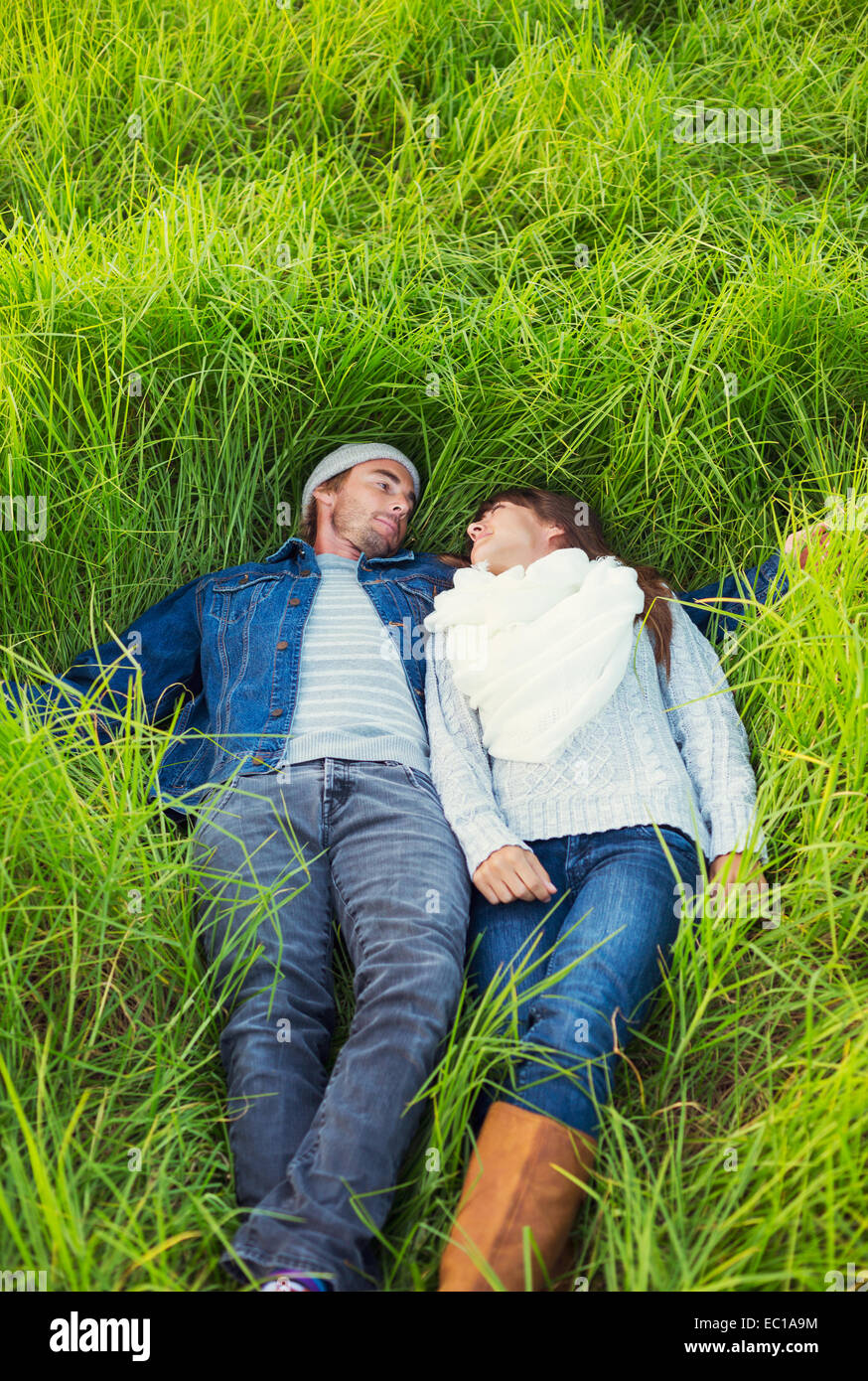 Jeune couple romantique dans l'amour à l'extérieur. Lying in Grassy Field Banque D'Images