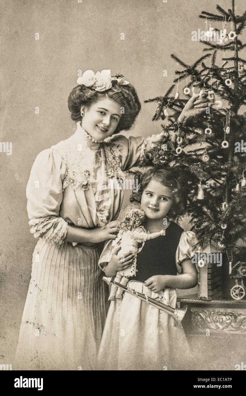 Heureuse mère et fille avec arbre de Noël et de jouets anciens. vintage sepia Photo avec grain de film original et flou Banque D'Images