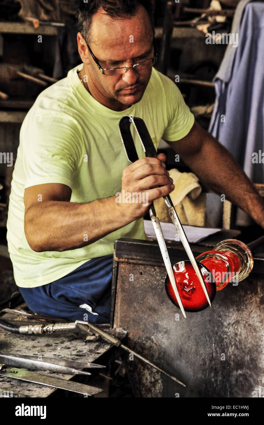 Bouilloire en verre de Murano, maître artisan, dans Foundry : façonner la fin d'un vase rouge, en utilisant 'borselle' (ou une pince pinces utilisées pour Banque D'Images