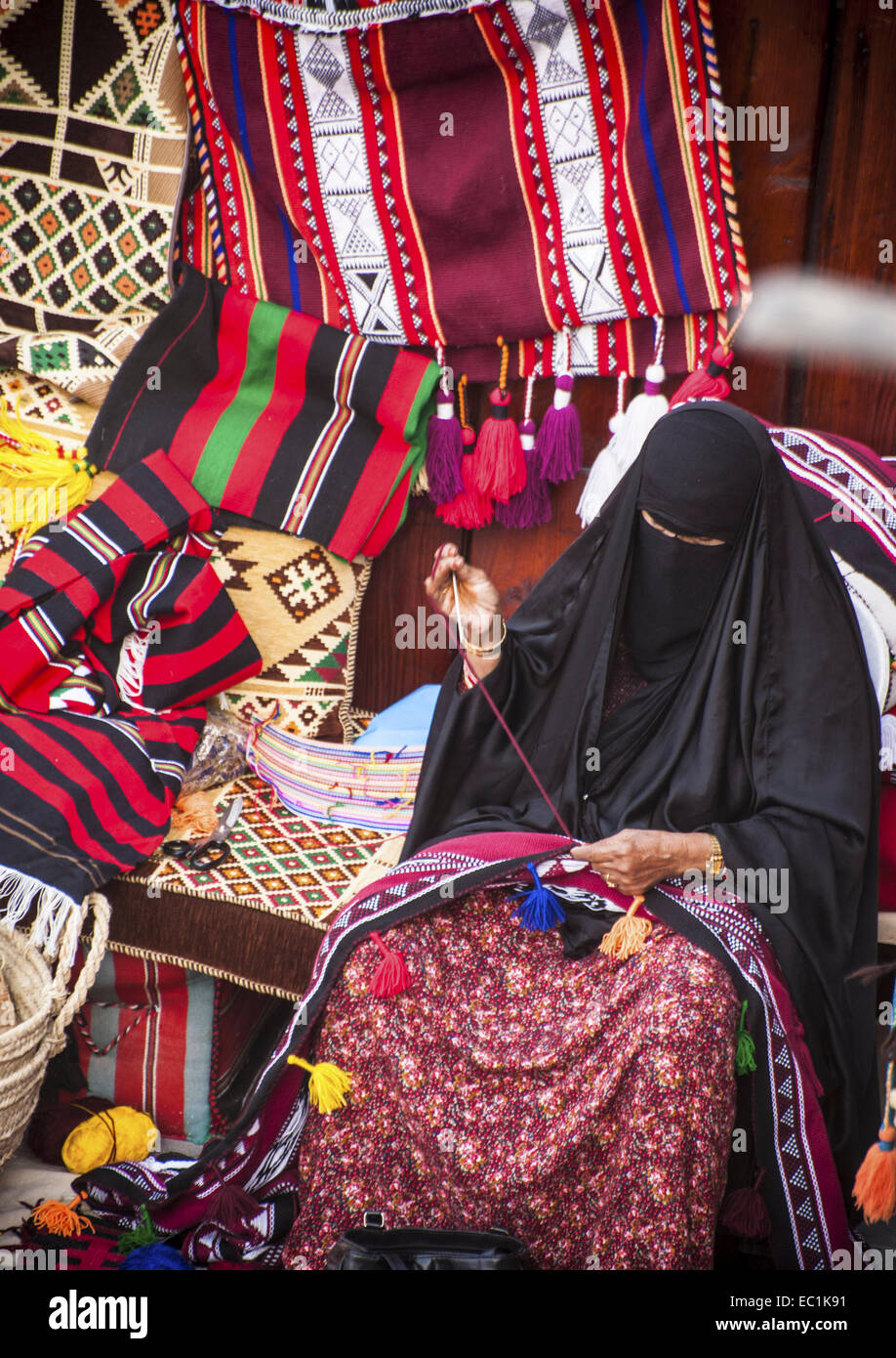 Femme arabe voilée sur les tapis de réparation / souk souk. Le souk Wakif. Une spécialité d'artisanat local. Les femmes portent l'abaya noire une longue Banque D'Images