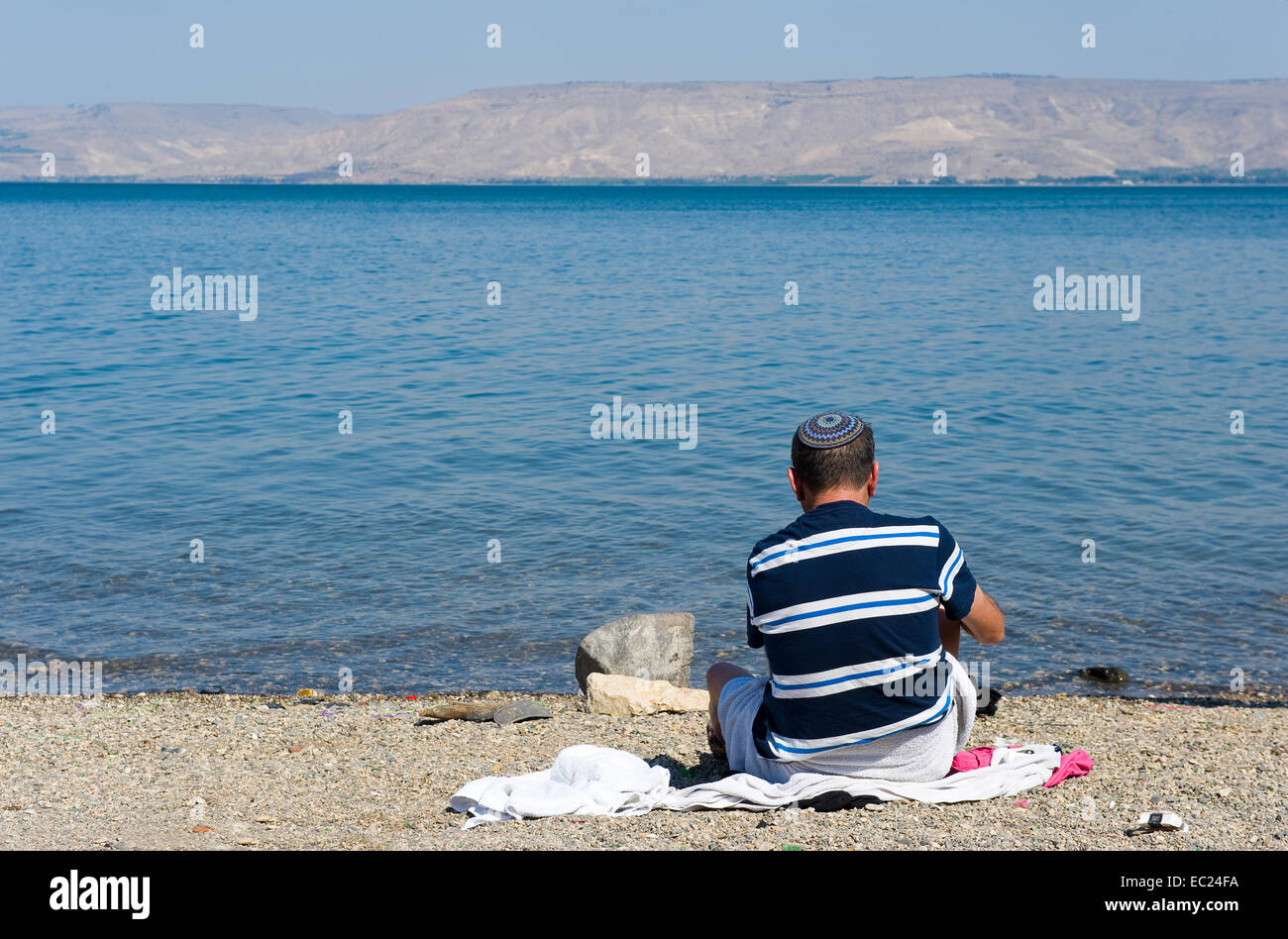 Un homme juif est assis sur la plage si la mer de Galilée, au sud de Tibériade Banque D'Images