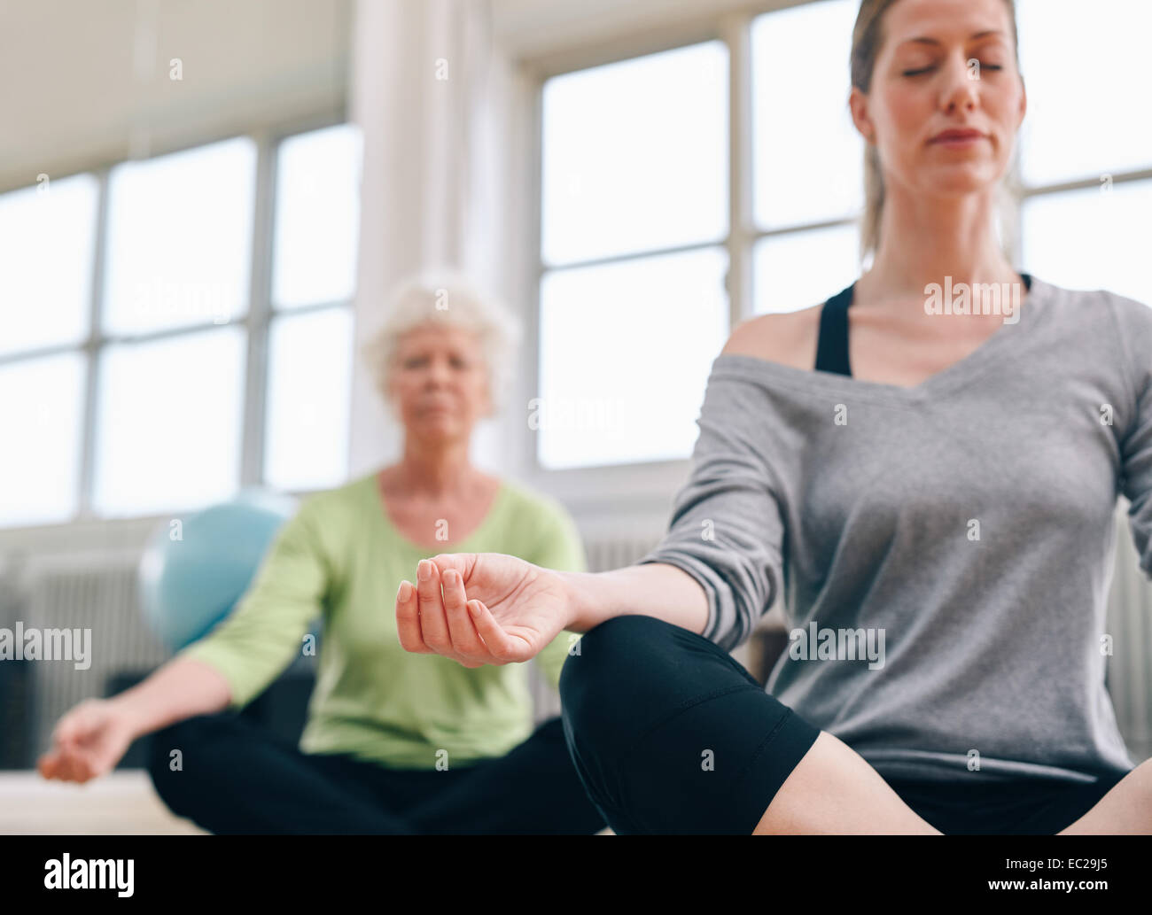 Tourné à l'intérieur de la médiation des femmes dans la classe de yoga. Se concentrer sur la main. Les femmes pratiquant le yoga fitness détendue au sport. Banque D'Images