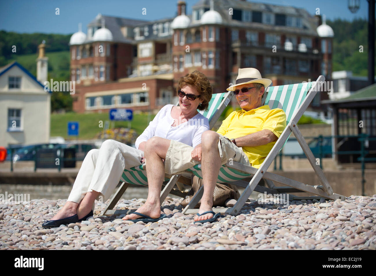 Un couple de personnes âgées assis sur des transats sur une plage Banque D'Images