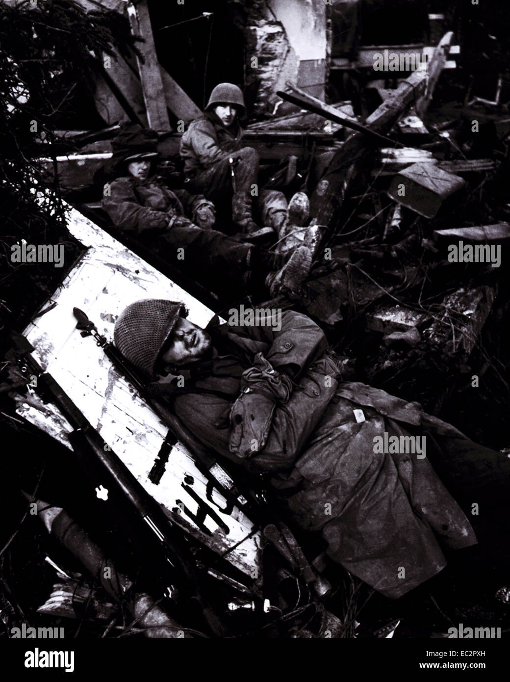 Des soldats américains se reposant au milieu des ruines de l'édifice, avec soldat couché sur plank en premier plan, sur la ligne Siegfried, vallée du Rhône, front allemand. février 1945. Banque D'Images