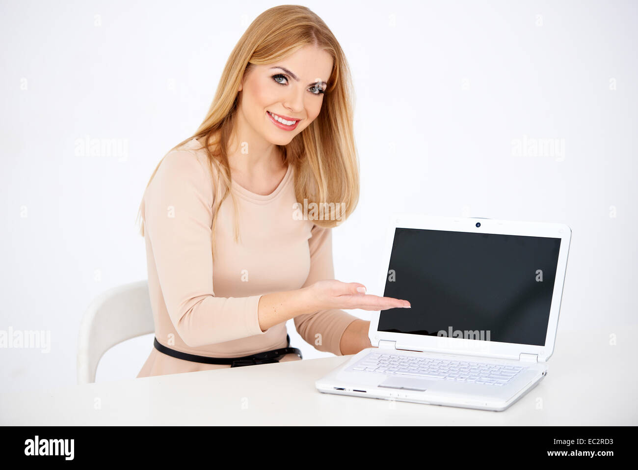 Sitting Smiling Woman Showing Laptop on Table Banque D'Images