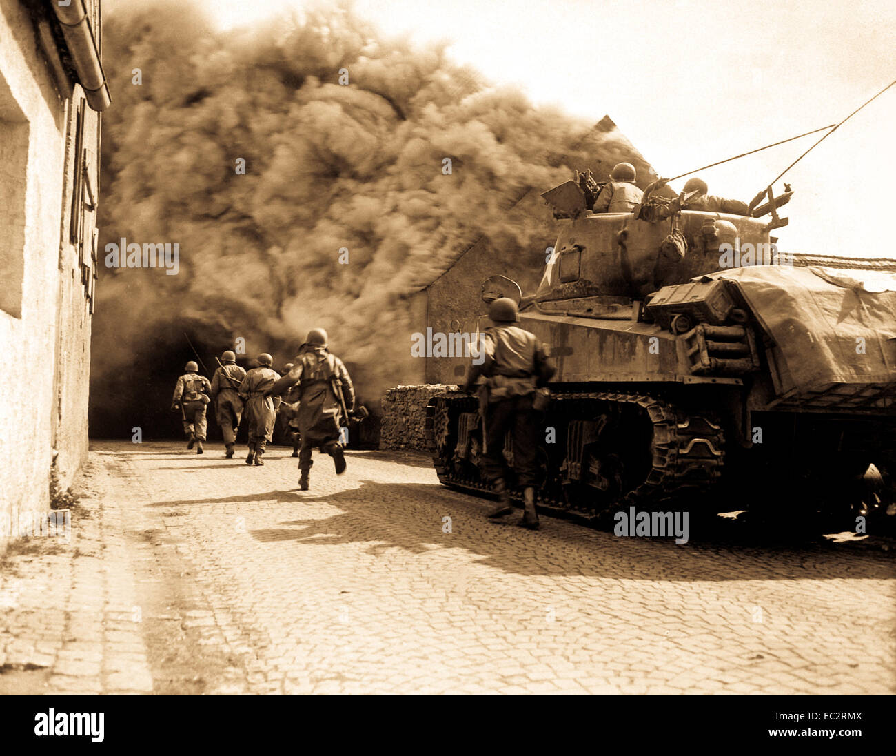 Soldats du 55e Bataillon d'infanterie blindée et le réservoir du 22e bataillon de chars, le mouvement par de fumée street. Wernberg, Allemagne. Le 22 avril 1945. Pvt. Joseph Scrippens. (Armée) Banque D'Images