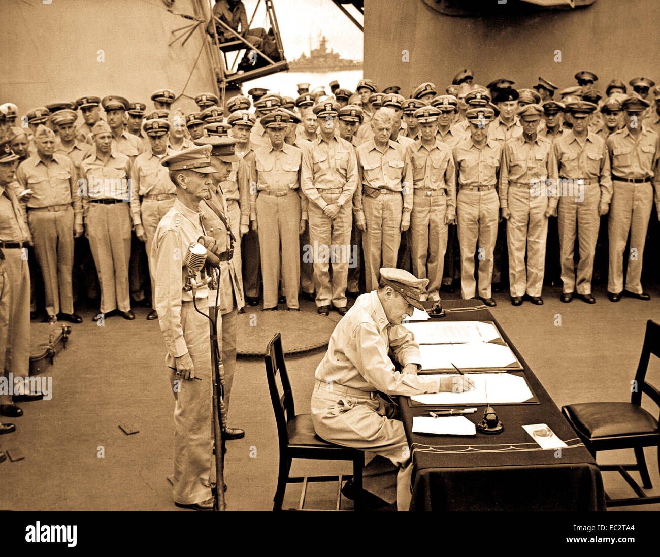 Le général Douglas MacArthur signe en tant que Commandant suprême des forces alliées au cours de cérémonies de remise officielle sur l'USS Missouri dans la baie de Tokyo. Derrière le général MacArthur sont le lieutenant-général Jonathan Wainwright et le lieutenant-général A. E. Percival. 2 Septembre, 1945. Le lieutenant C. F. Wheeler. (Marine) Banque D'Images