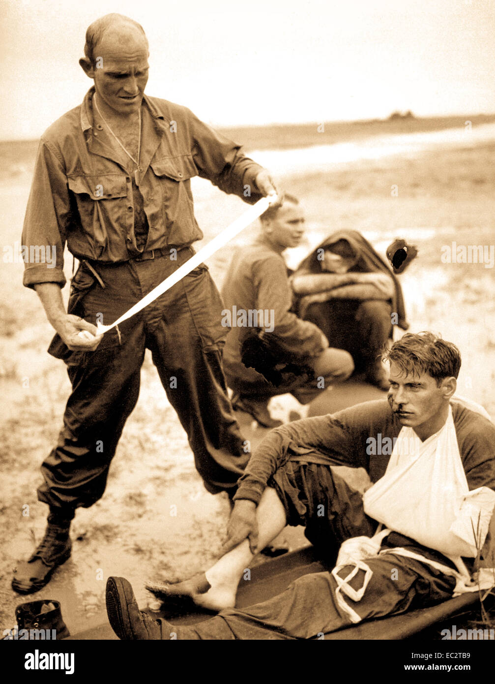 Un char moyen américain a frappé une mine terrestre japonais dans l'élançant à tacloban bande d'air pendant les premières étapes de l'invasion des Philippines. Ici, l'un des blessés de l'épave réservoir se pansée par un médecin corpsman. 1944. Banque D'Images
