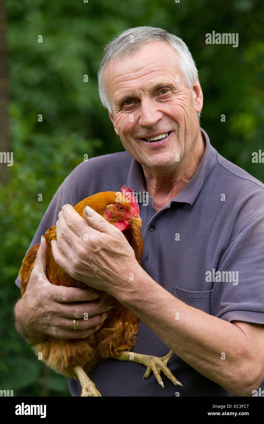 Portrait d'un agriculteur avec une poule ou poulet heureux comme un symbole d'nachhlatiges handlen, de la nature et de l'amour pour les animaux Banque D'Images