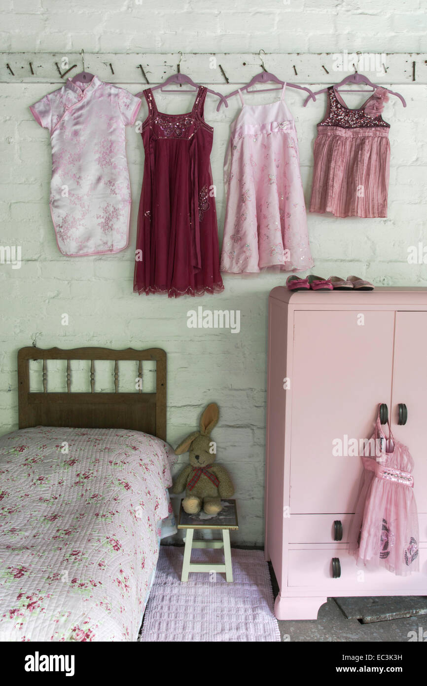 Petites filles robes rouges et roses de raccrocher sur lit et armoire Banque D'Images