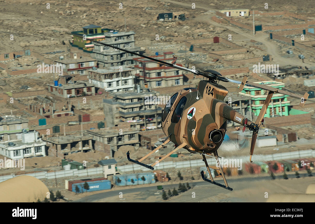 Un Afghan Air Force MD 530F Cayuse hélicoptère vole à basse altitude au-dessus du guerrier une zone résidentielle, le 6 décembre 2014 à Kaboul, Afghanistan. Le MD 530F est un hélicoptère polyvalent utilisé pour scout, fournir une escorte armée et à proximité de l'attaque aérienne de la force aérienne afghane. Banque D'Images