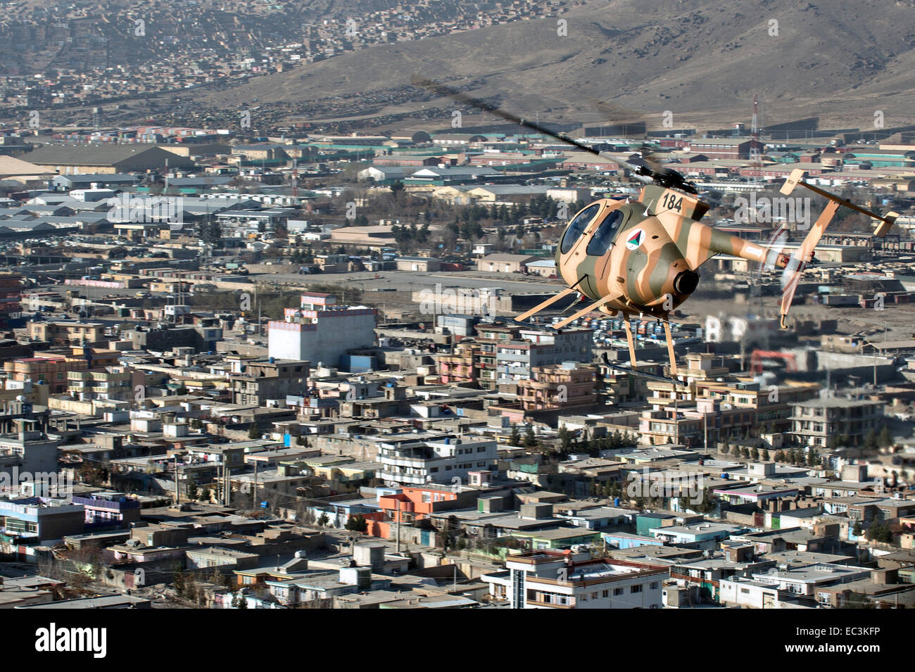 Un Afghan Air Force MD 530F Cayuse hélicoptère vole à basse altitude au-dessus du guerrier une zone résidentielle, le 6 décembre 2014 à Kaboul, Afghanistan. Le MD 530F est un hélicoptère polyvalent utilisé pour scout, fournir une escorte armée et à proximité de l'attaque aérienne de la force aérienne afghane. Banque D'Images