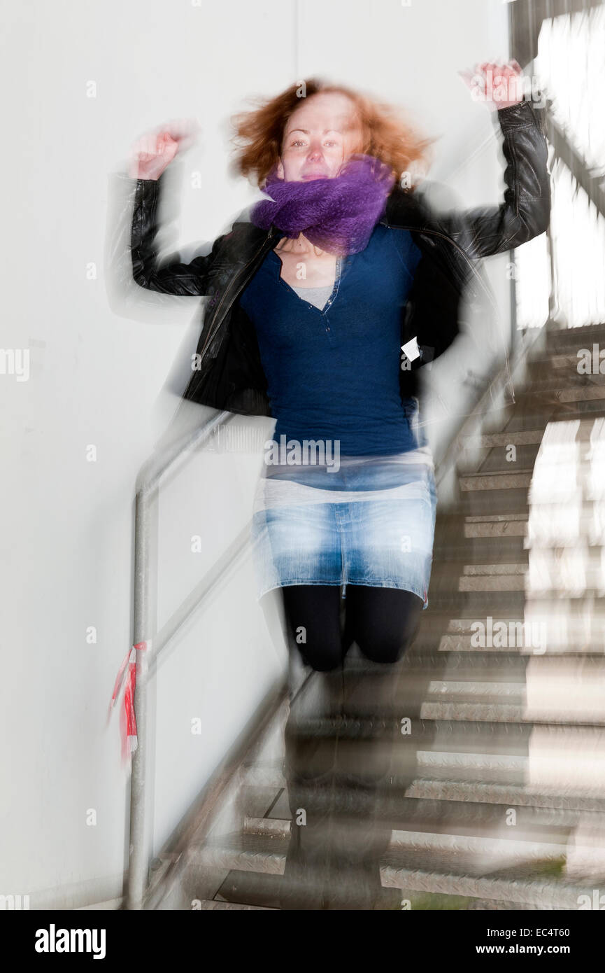 Jeune femme sautant dans un escalier Banque D'Images
