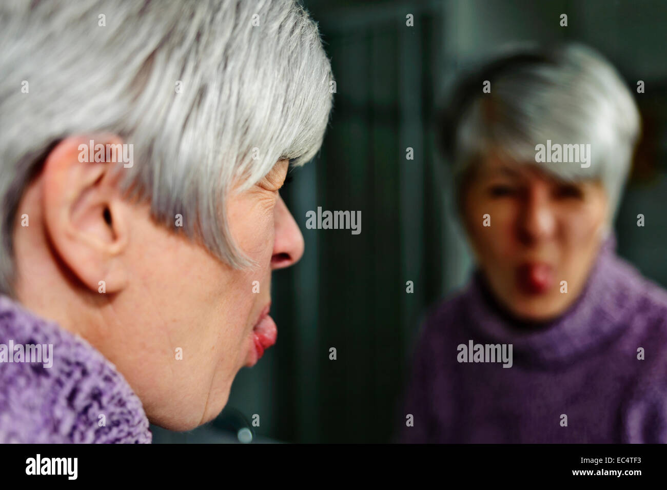 Femme, 50 , regardez dans le miroir et tire un visage Banque D'Images