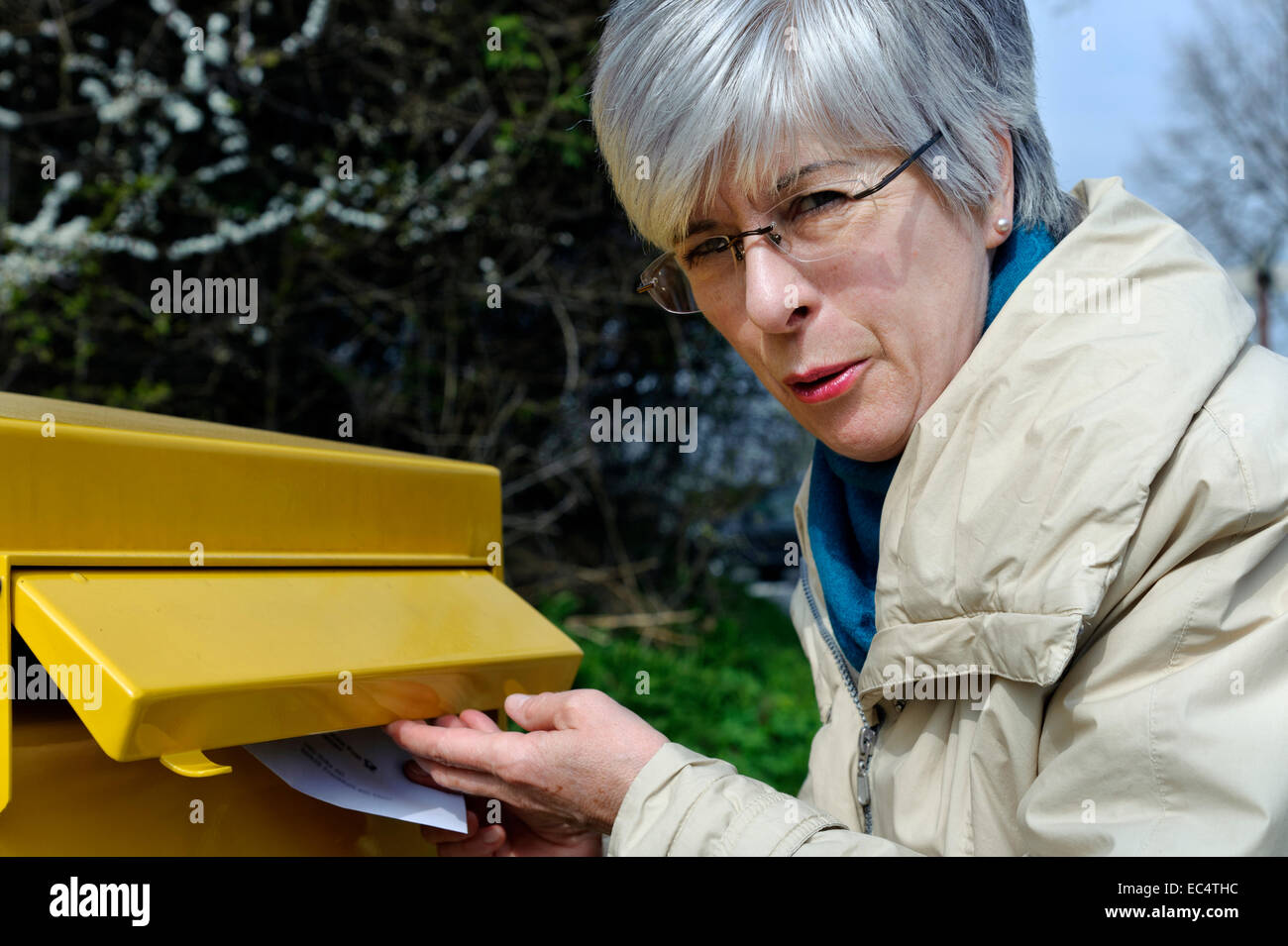 Une femme met une lettre dans la boîte aux lettres Banque D'Images